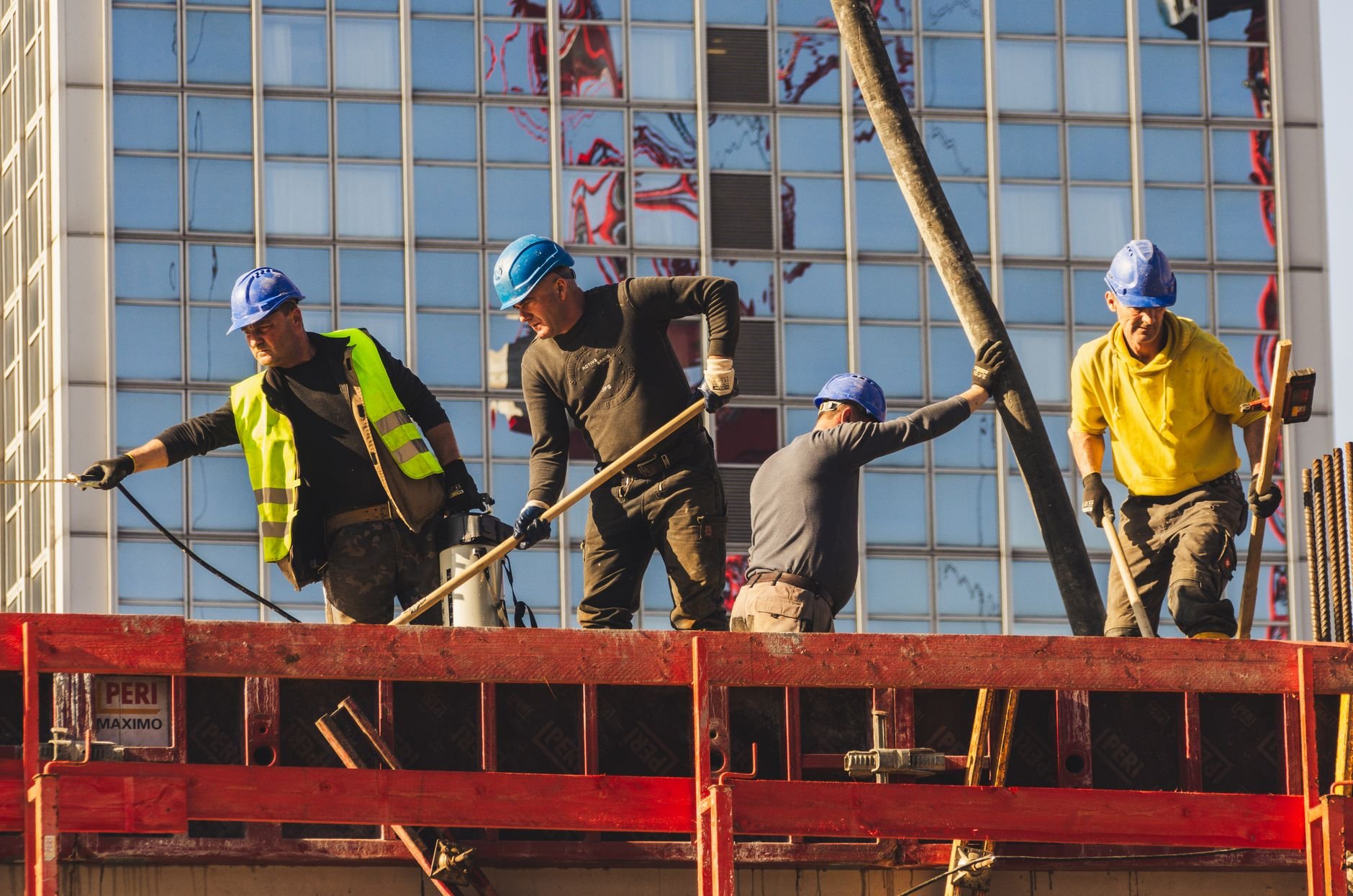 A group of construction workers in safety gear actively working on a building site.
